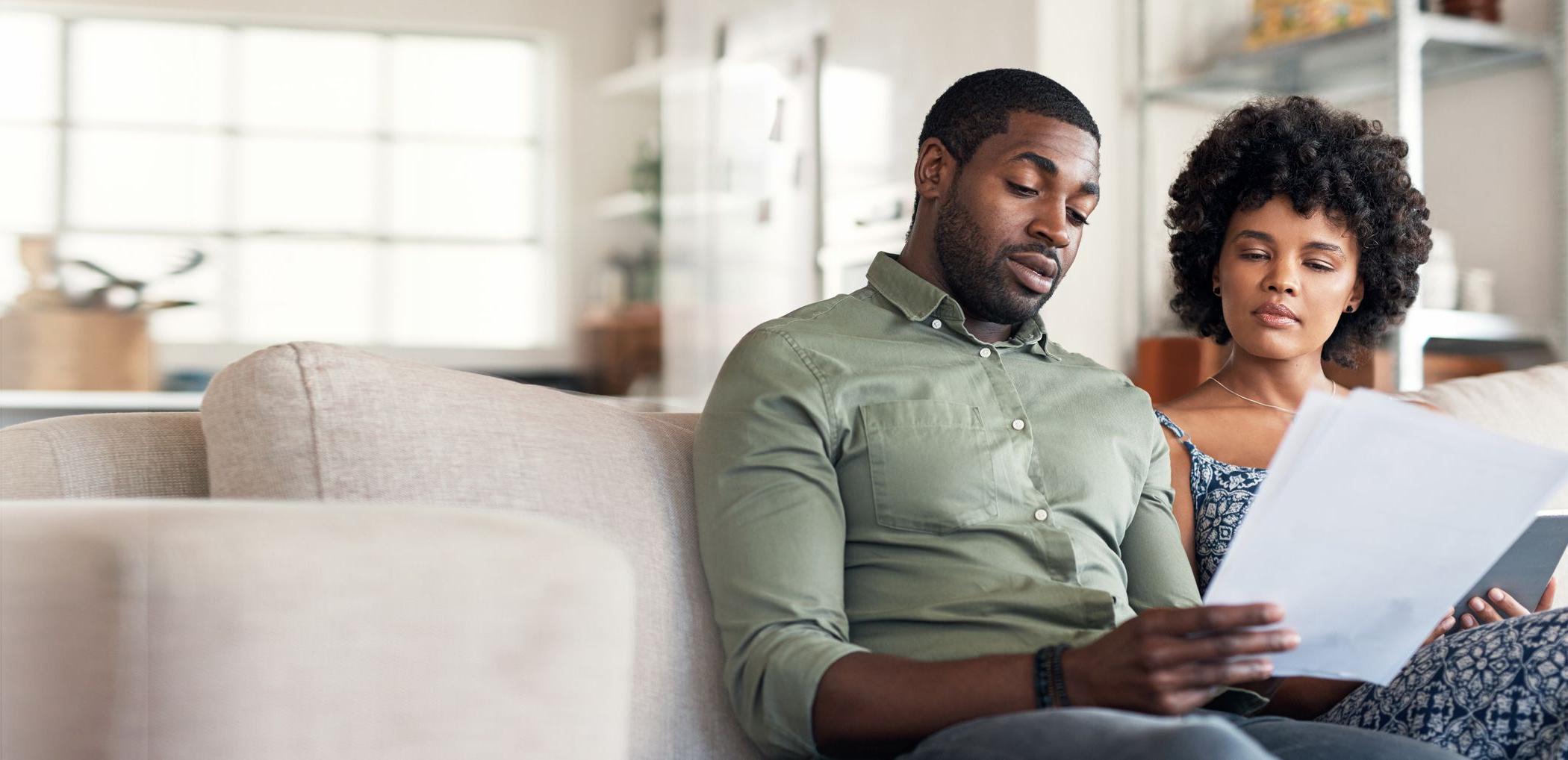 A couple reviews their budget plan from their couch at home.